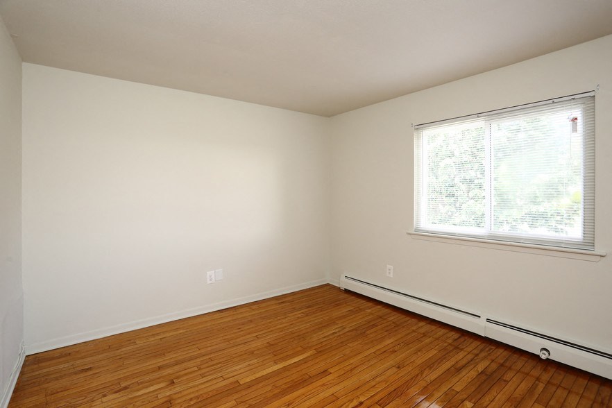 an empty room with wood floors and a window