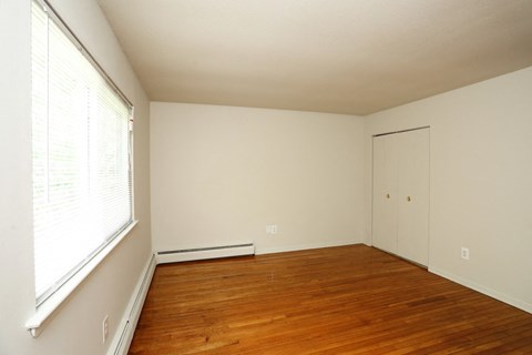 a bedroom with wood floors and a large window and white walls