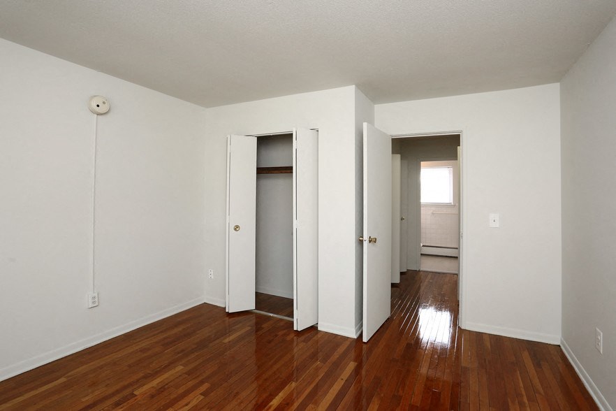 an empty living room with wood floors and white walls
