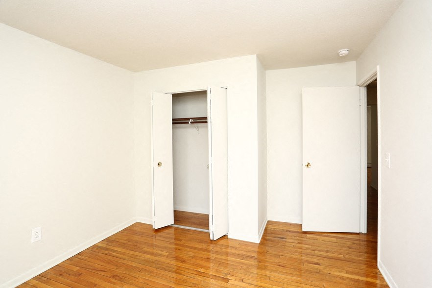 an empty room with white walls and wooden floors and a closet