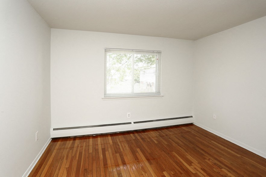 an empty room with a window and wooden floors