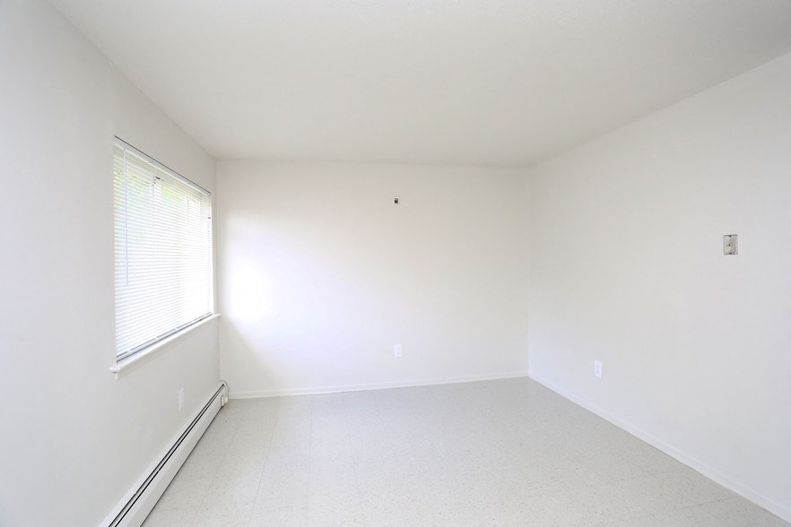 an empty room with a window and white walls