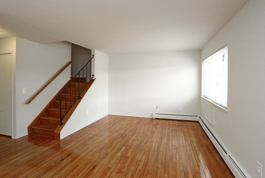 an empty living room with wood floors and a staircase