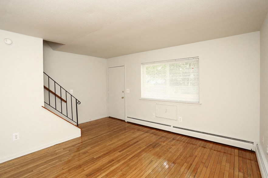an empty living room with a hard wood floor and a window