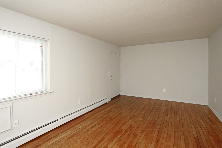 an empty room with wood flooring and a window