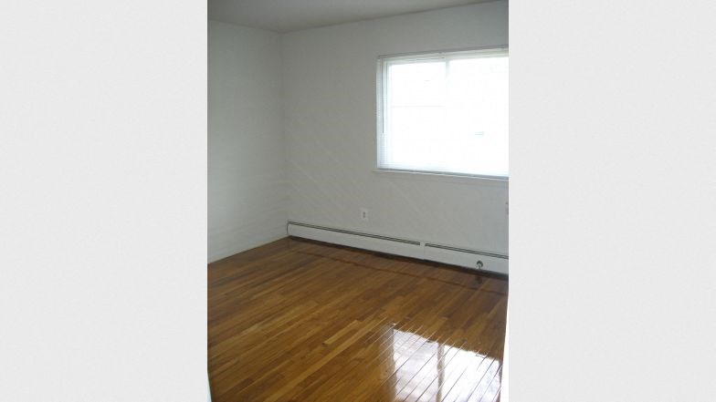 an empty room with a window and wooden floors