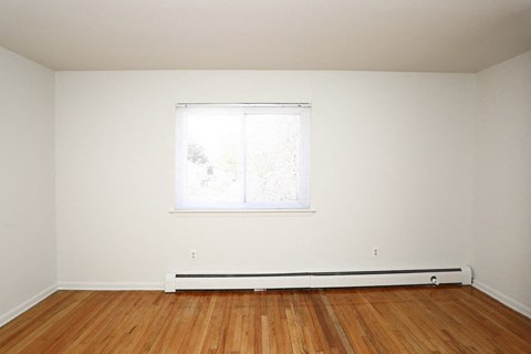 an empty room with a window and wooden floors