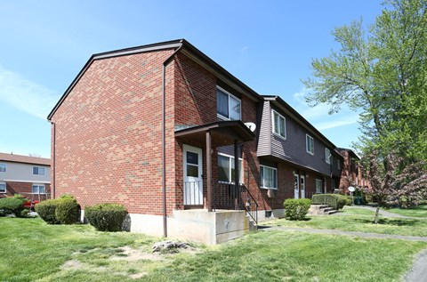 the side of a brick apartment building with grass and trees