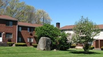 a large rock in the grass in front of a building