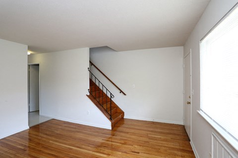 a living room with wood floors and a staircase