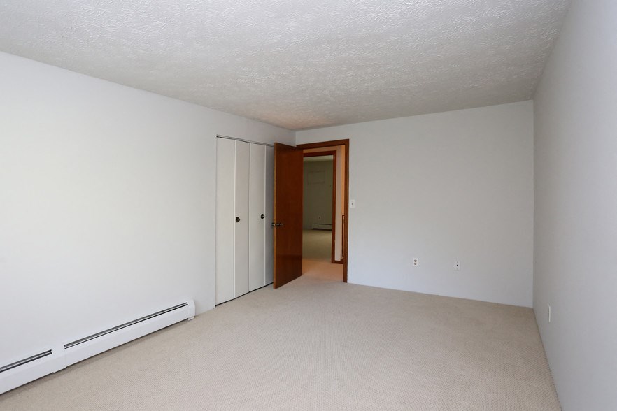 a bedroom with white walls and a door to a hallway