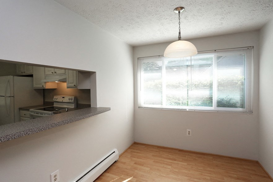 an empty living room with a large window and a kitchen