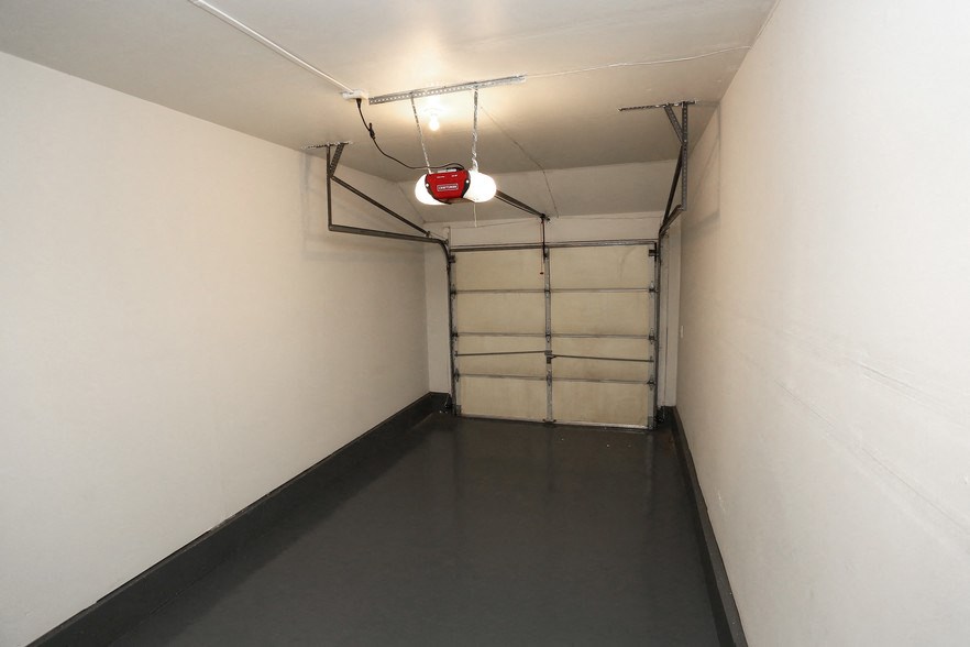 a long hallway with a red light on the ceiling and a dark floor