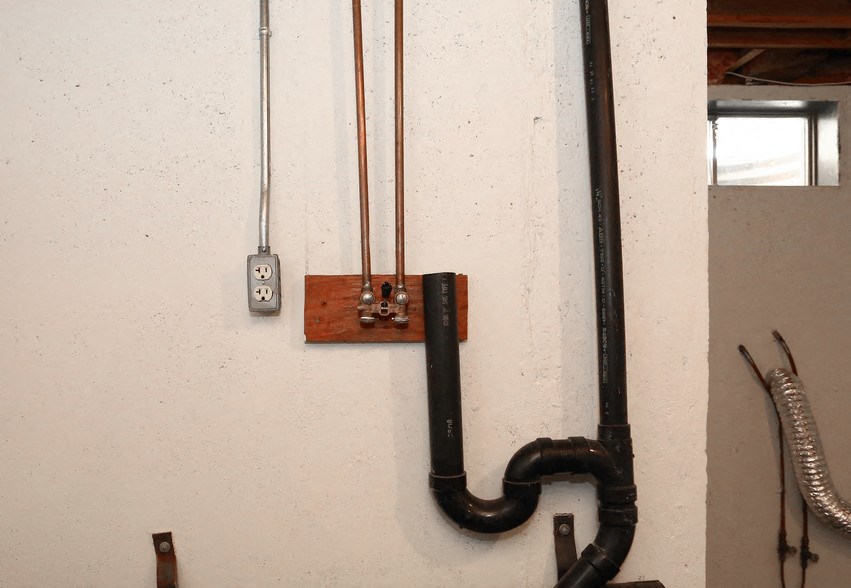 a wall with a pipe and tools on it