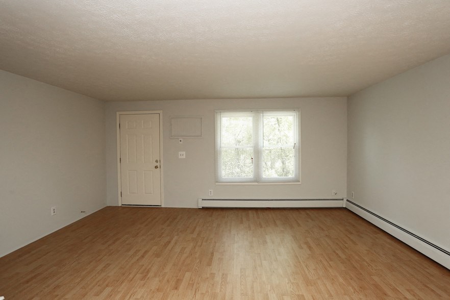 the living room of an empty house with wood floors and a window