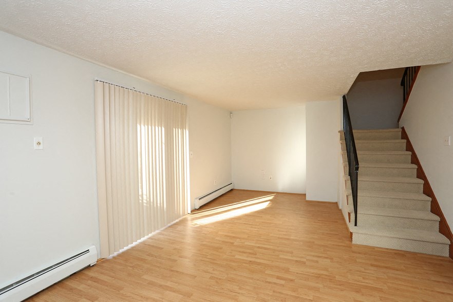 the living room and staircase of an empty house with wood flooring