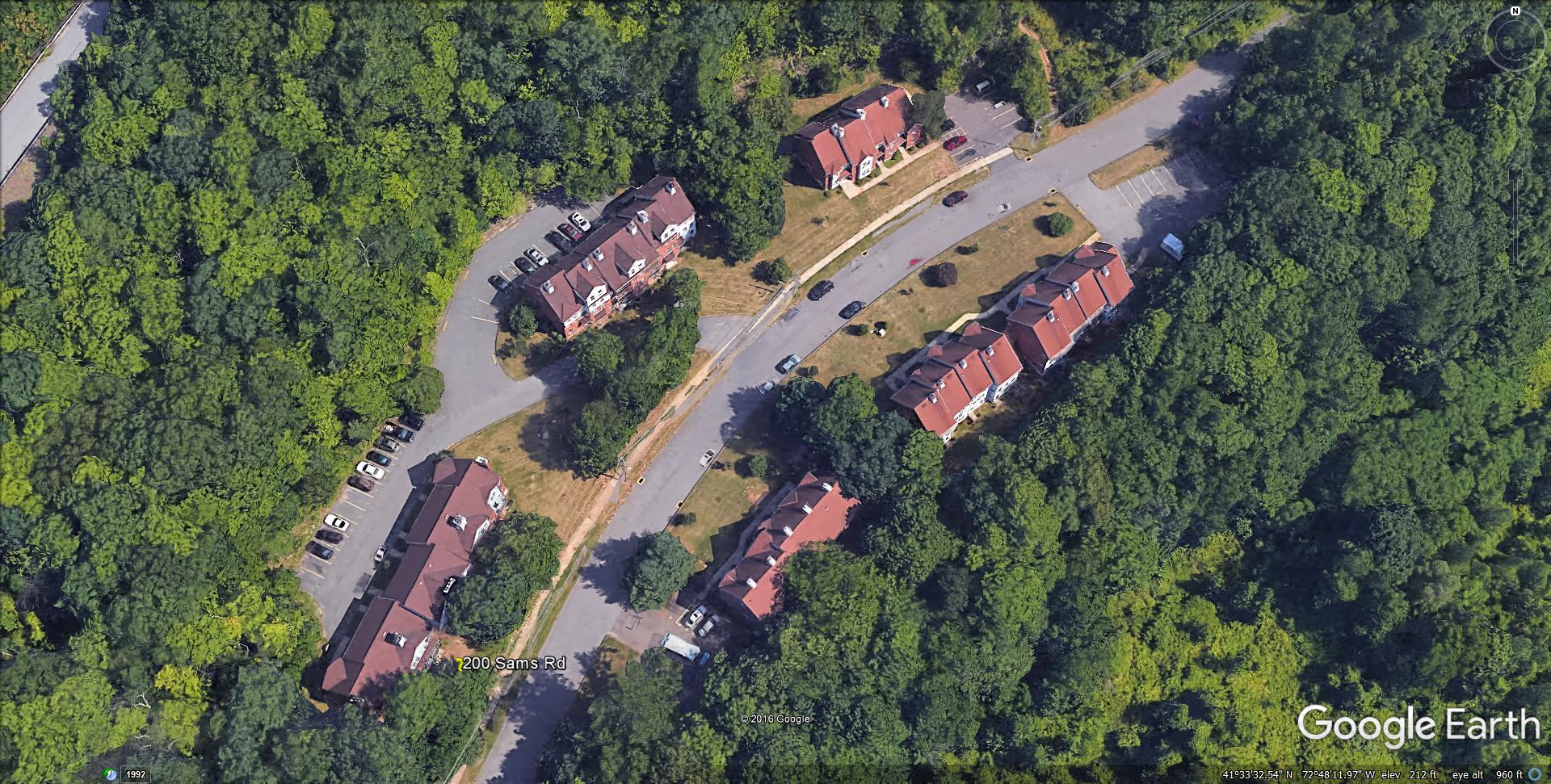 an aerial view of houses and a road next to a forest