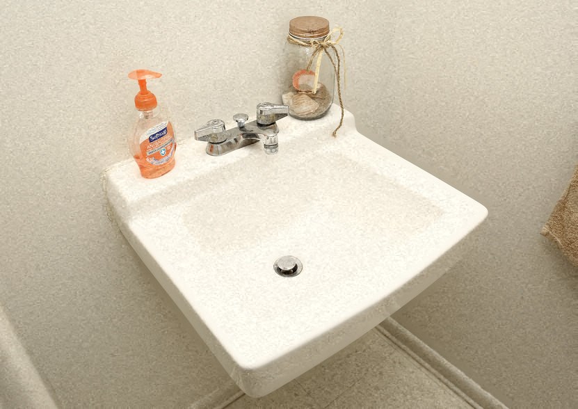 a white sink in a bathroom with a soap dispenser