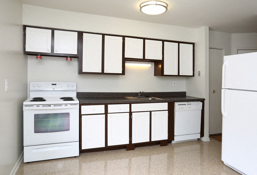 an empty kitchen with white appliances and white cabinets