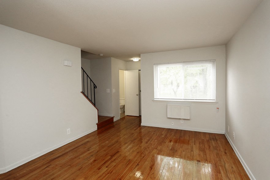 an empty living room with a hard wood floor and a window
