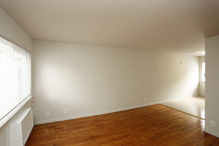 the living room and dining room of a house with a wooden floor