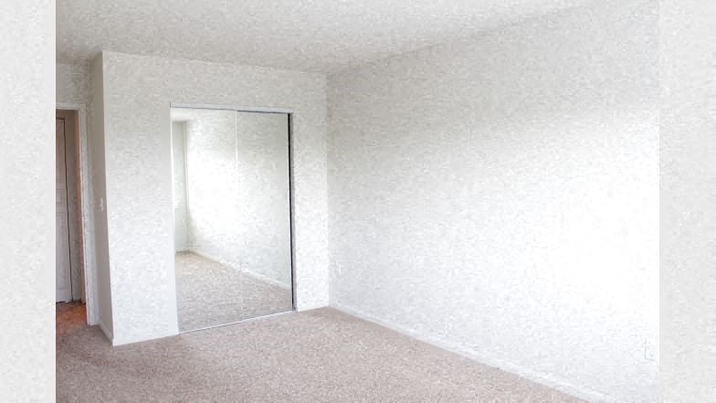 an empty room with a white wall and a mirror