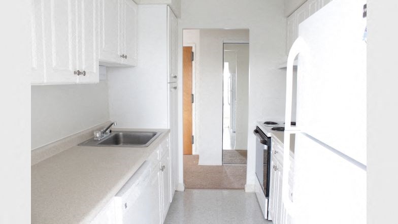 an empty kitchen with a sink and a refrigerator