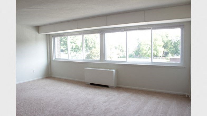 an empty living room with a window and a radiator