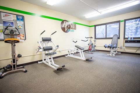 a gym with three exercise machines and weights in a room with a window