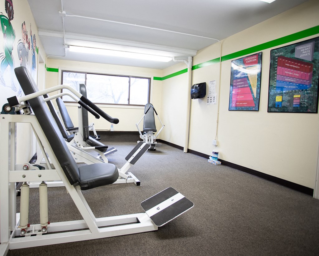 a gym with a treadmill and weights in a room with a window
