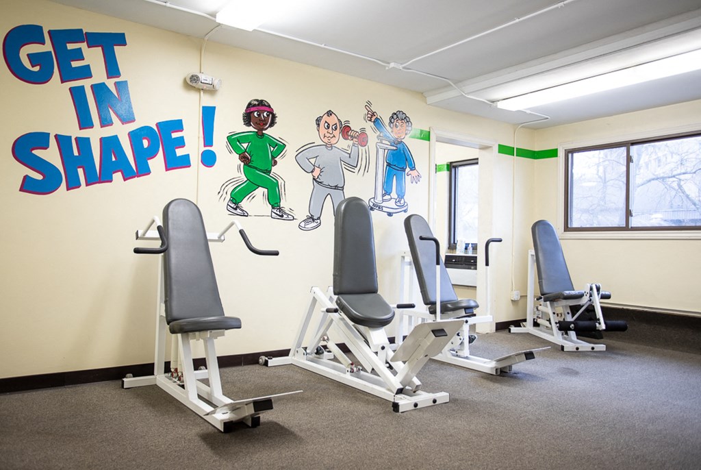 a gym with cardio equipment and a mural on the wall