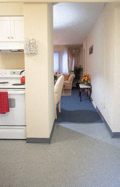 a kitchen and living room with a white stove and refrigerator