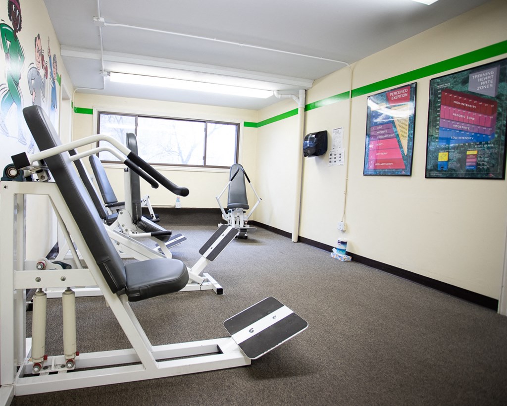 a gym with a treadmill and weights in a room with a window