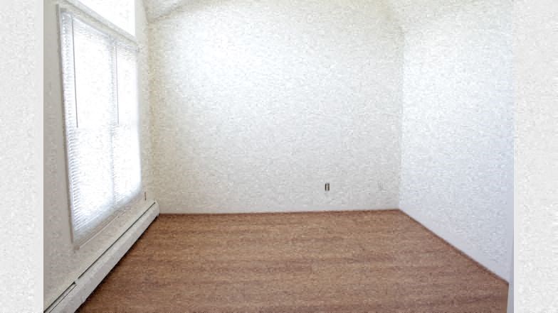 an empty room with a window and a wooden floor