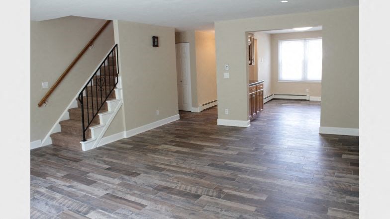 a living room with a staircase and a hard wood floor