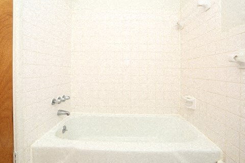 a white bath tub in a white tiled bathroom