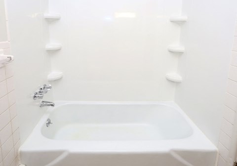 a white bath tub in a bathroom with two white shelves