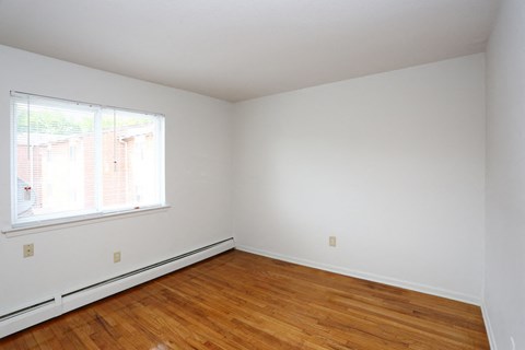 an empty room with wood floors and a window