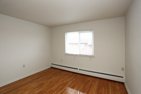 a bedroom with a window and wooden floors