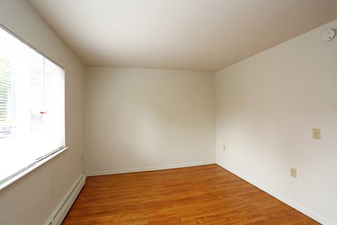 an empty room with wooden floors and a large window