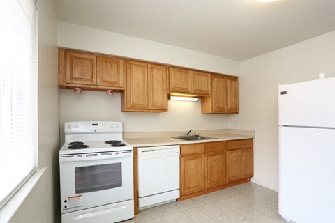 an empty kitchen with white appliances and wooden cabinets