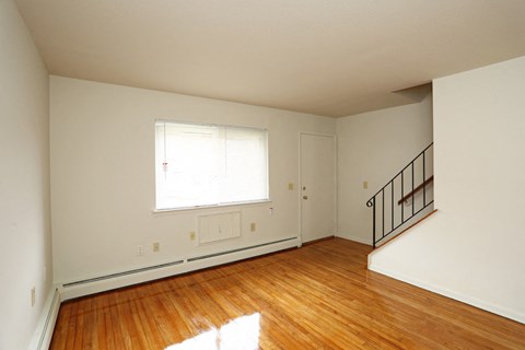 an empty living room with wood floors and a window