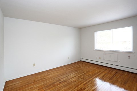 an empty room with wood floors and a window