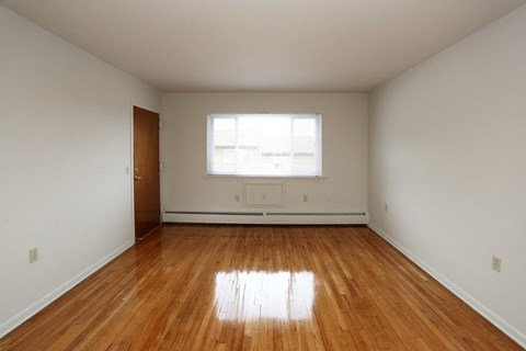 the living room of an empty house with wood floors and a window