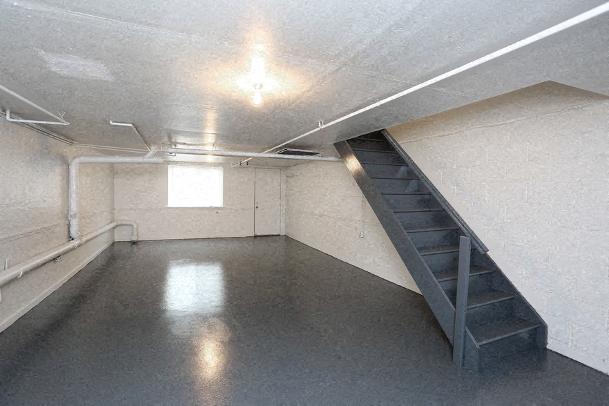 a empty basement with a staircase and a window