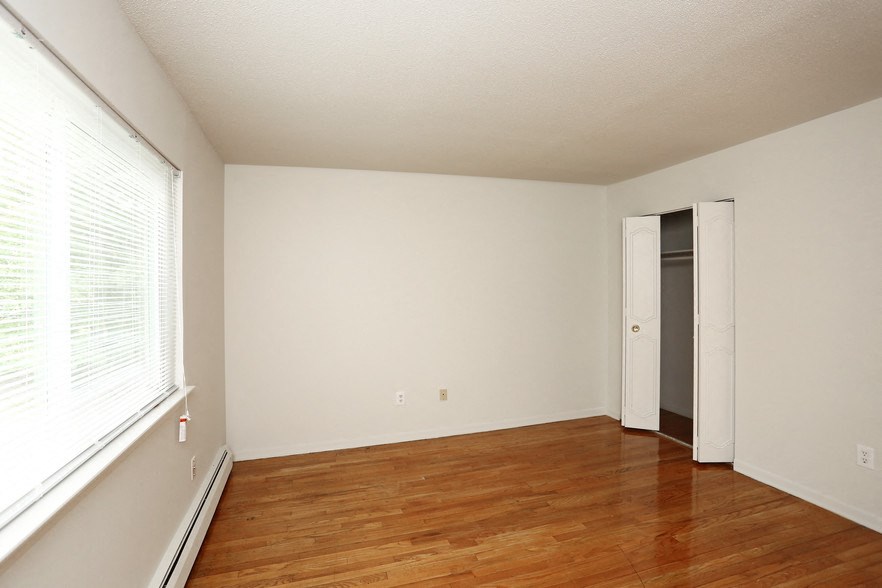 an empty living room with wood floors and a large window