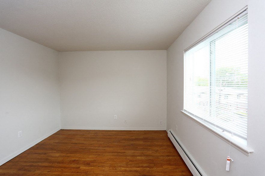 an empty room with a large window and wooden floors