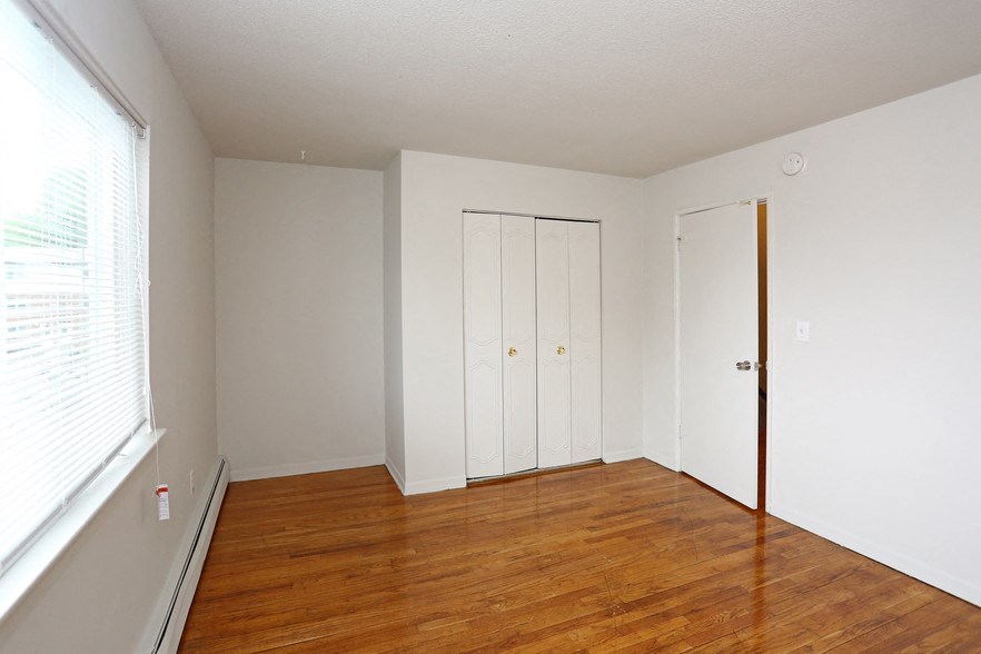 an empty living room with wood floors and white walls