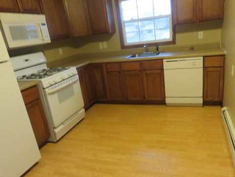 an empty kitchen with wooden floors and white appliances