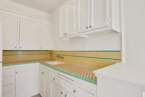 A kitchen with white cabinets and a yellow tiled backsplash.